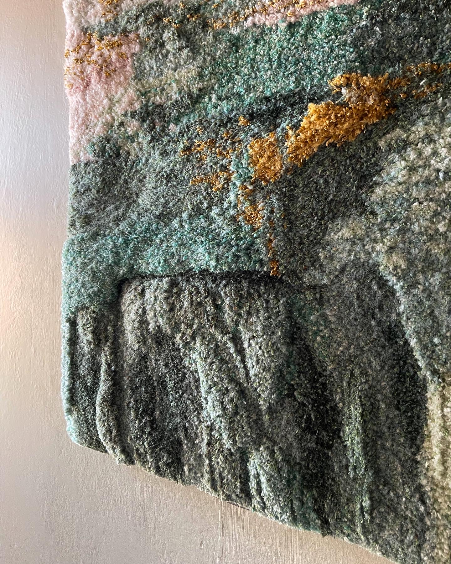 close up of handtufted green pink gold tapestry