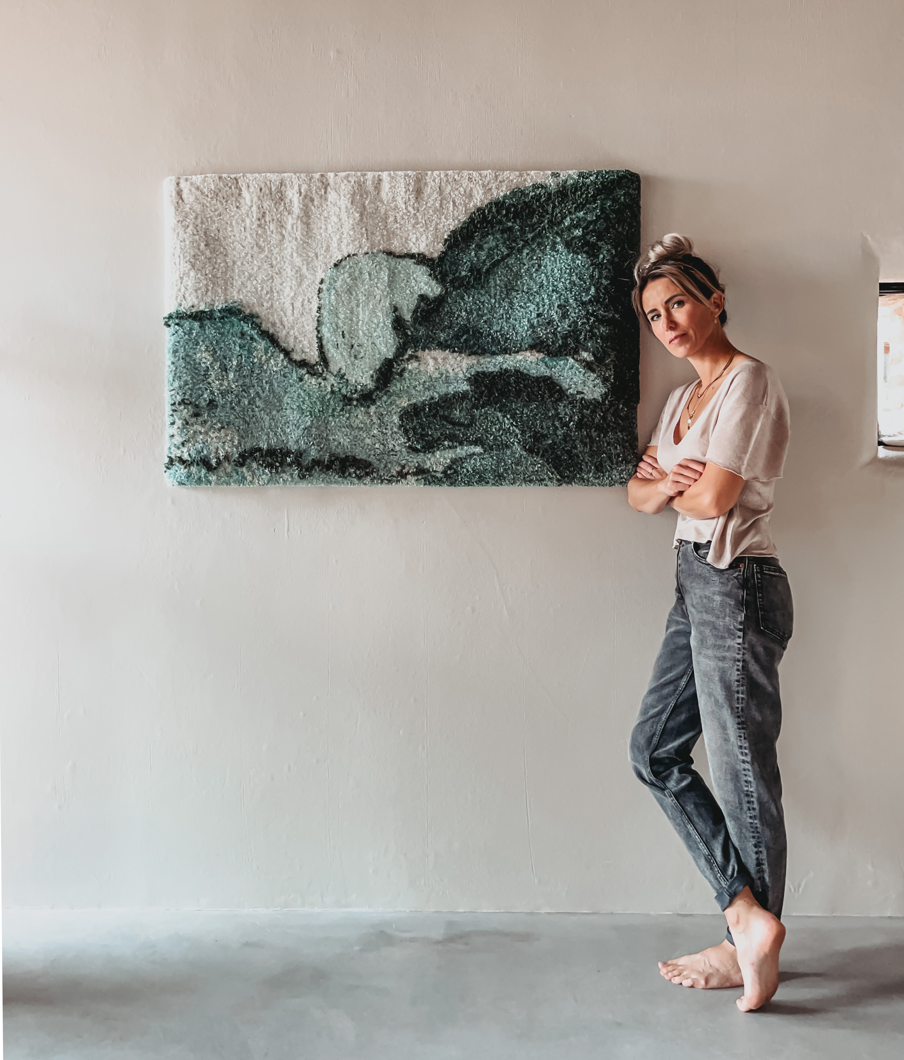 fiber artist standing before handtufted rug