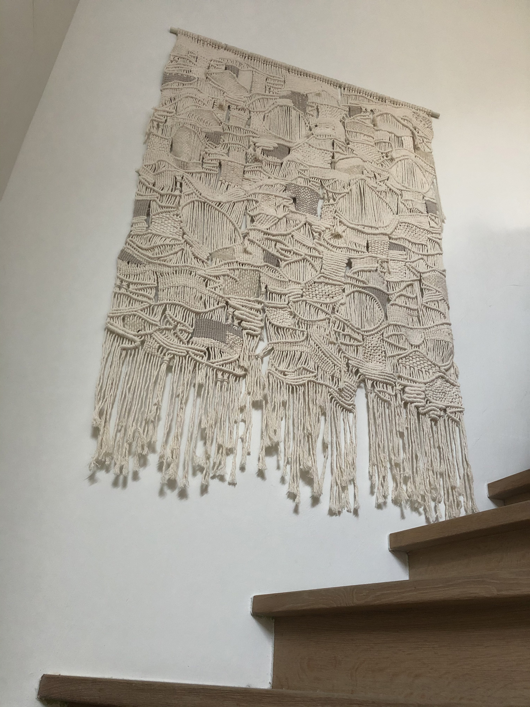 large handmade modern macrame wallhanging in natural colors with oak staircase